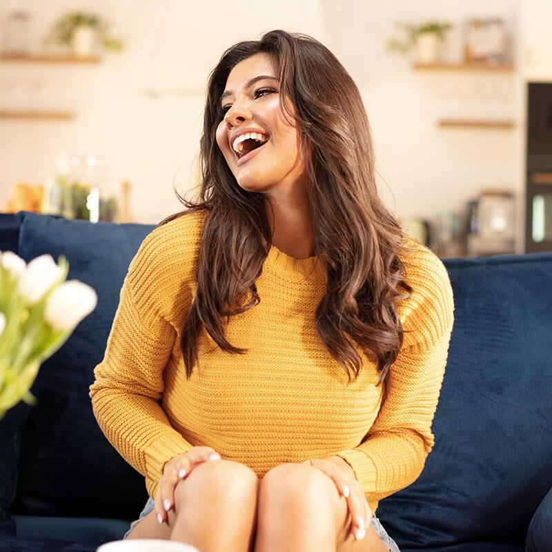 Girl on couch smiling.